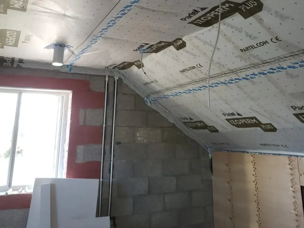 Airtight membrane taped across a ceiling and down the walls of a room under construction