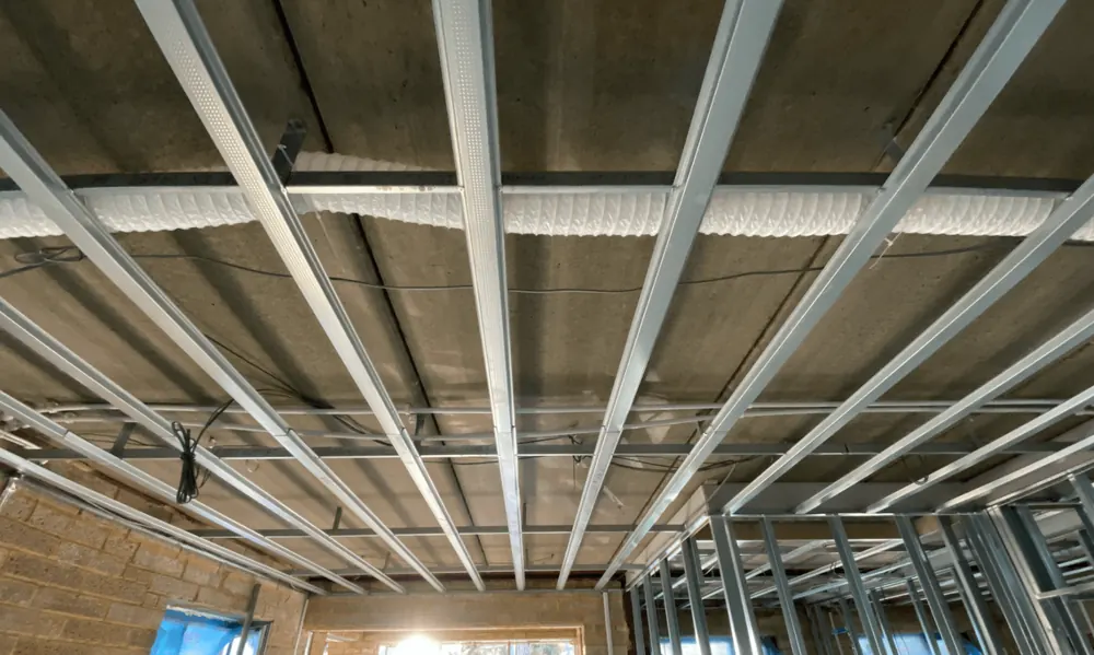 Metal frame ceiling grid installed below a concrete soffit with services running through it